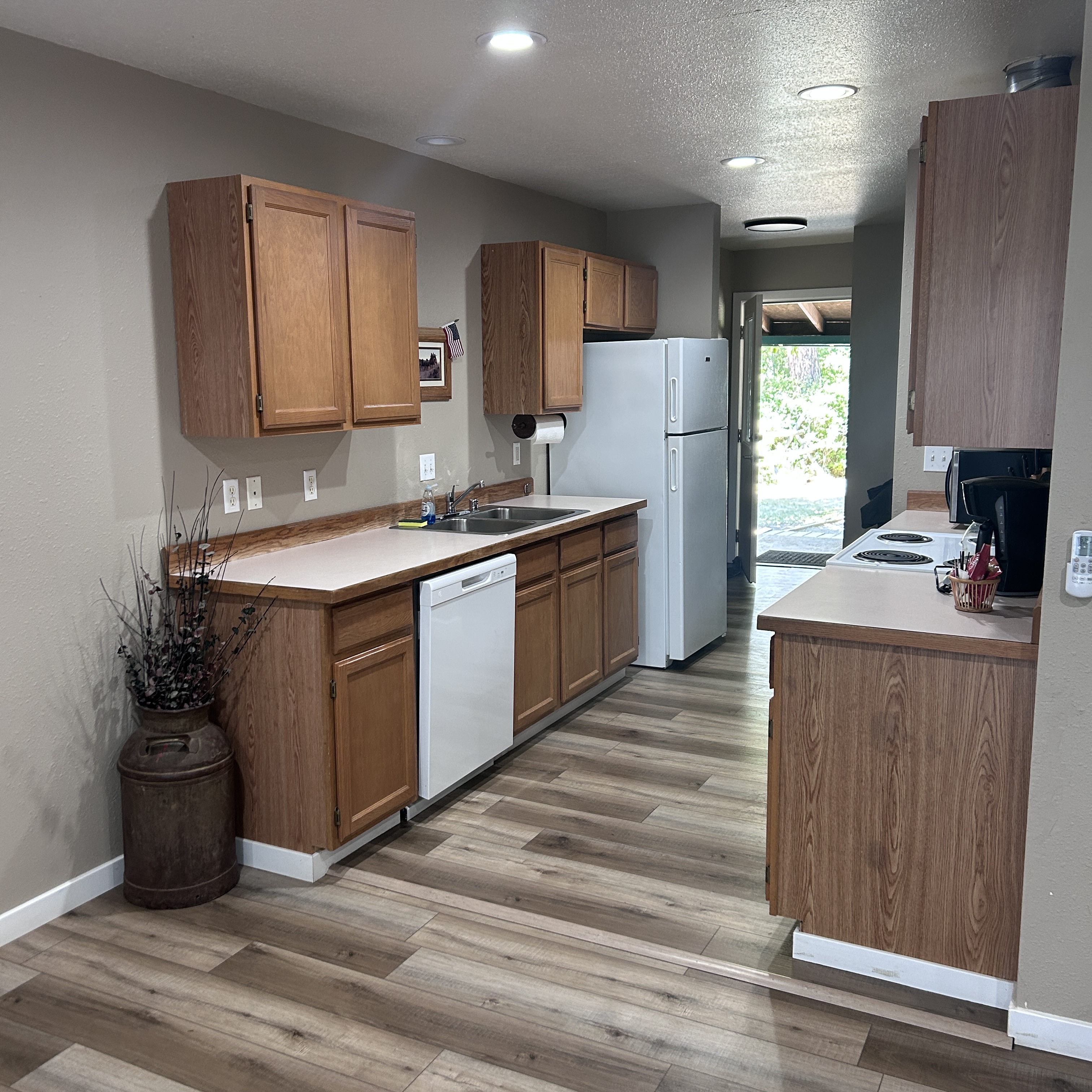 Lake View Condos - Modern kitchen interior with wood cabinets, white appliances, and wood-look flooring