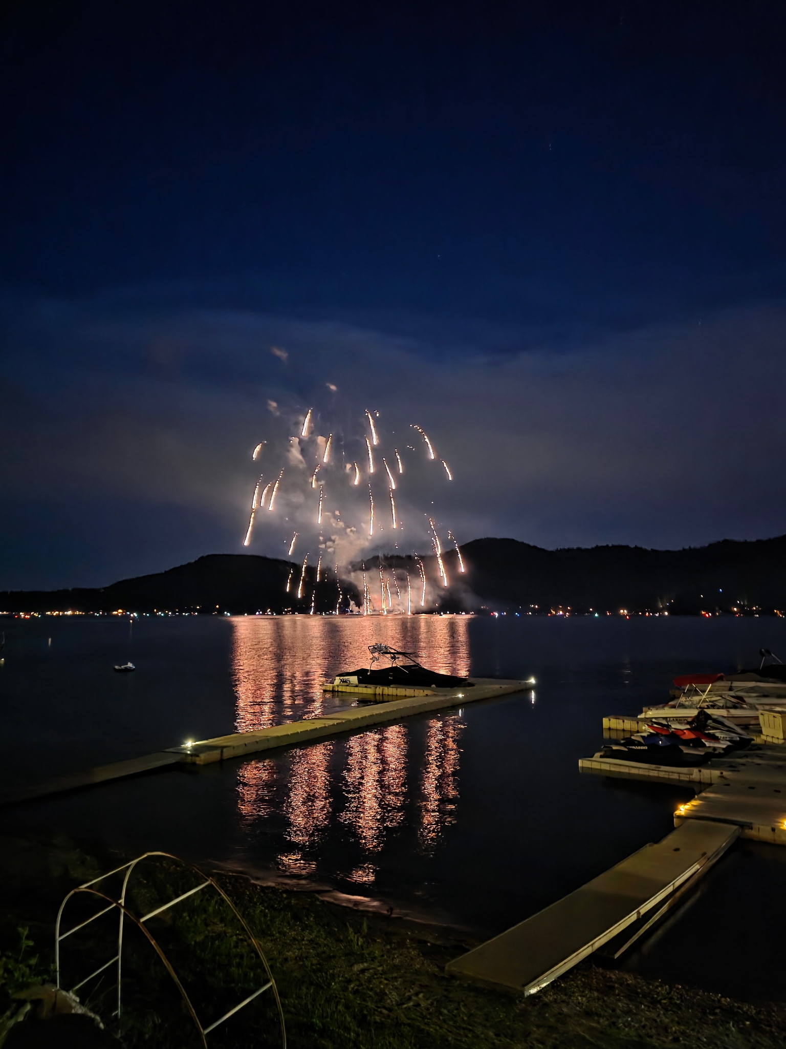 Spectacular fireworks display over lake with reflections and boat docks