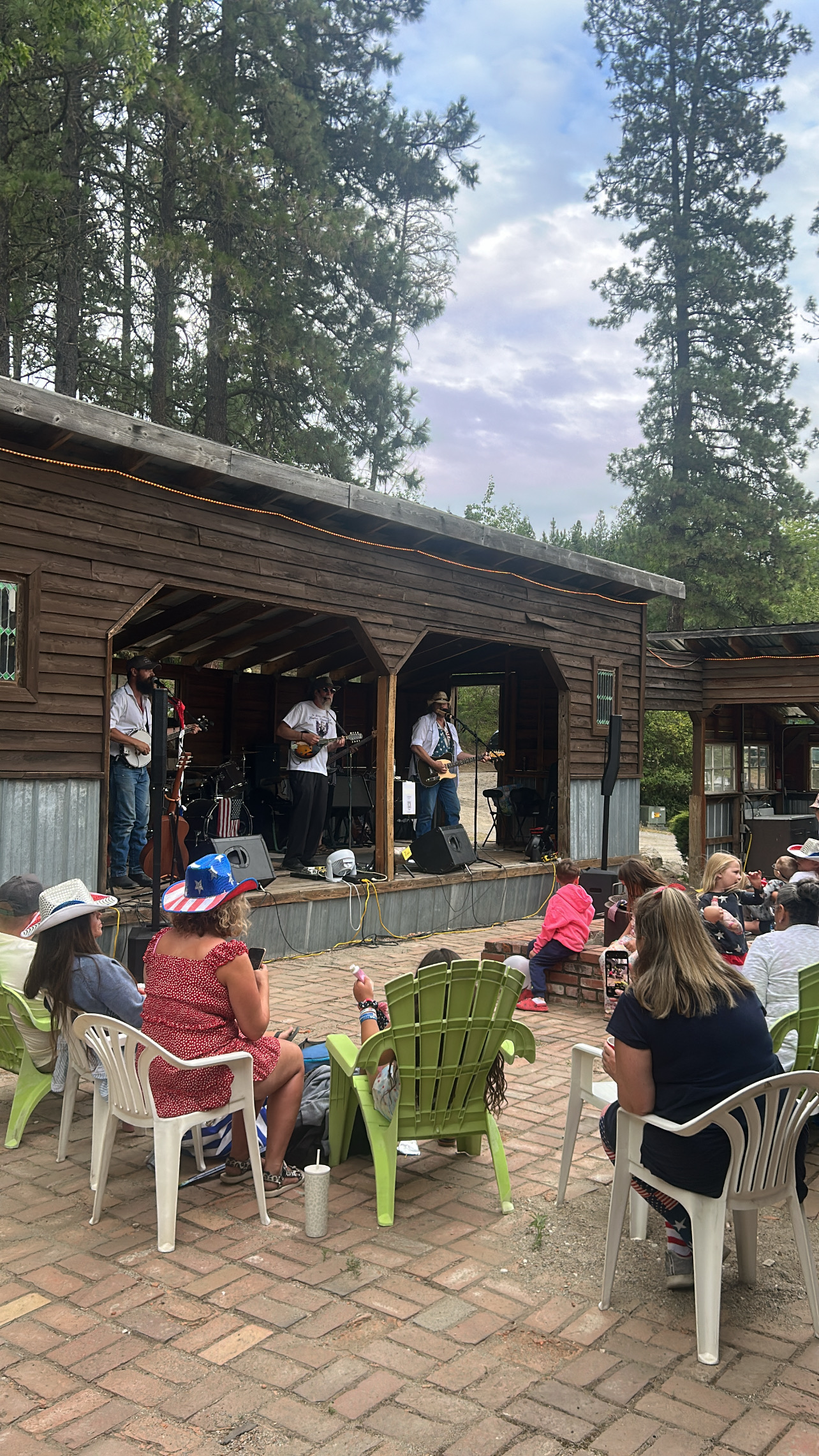 Live music performance on outdoor wooden stage with audience on brick patio
