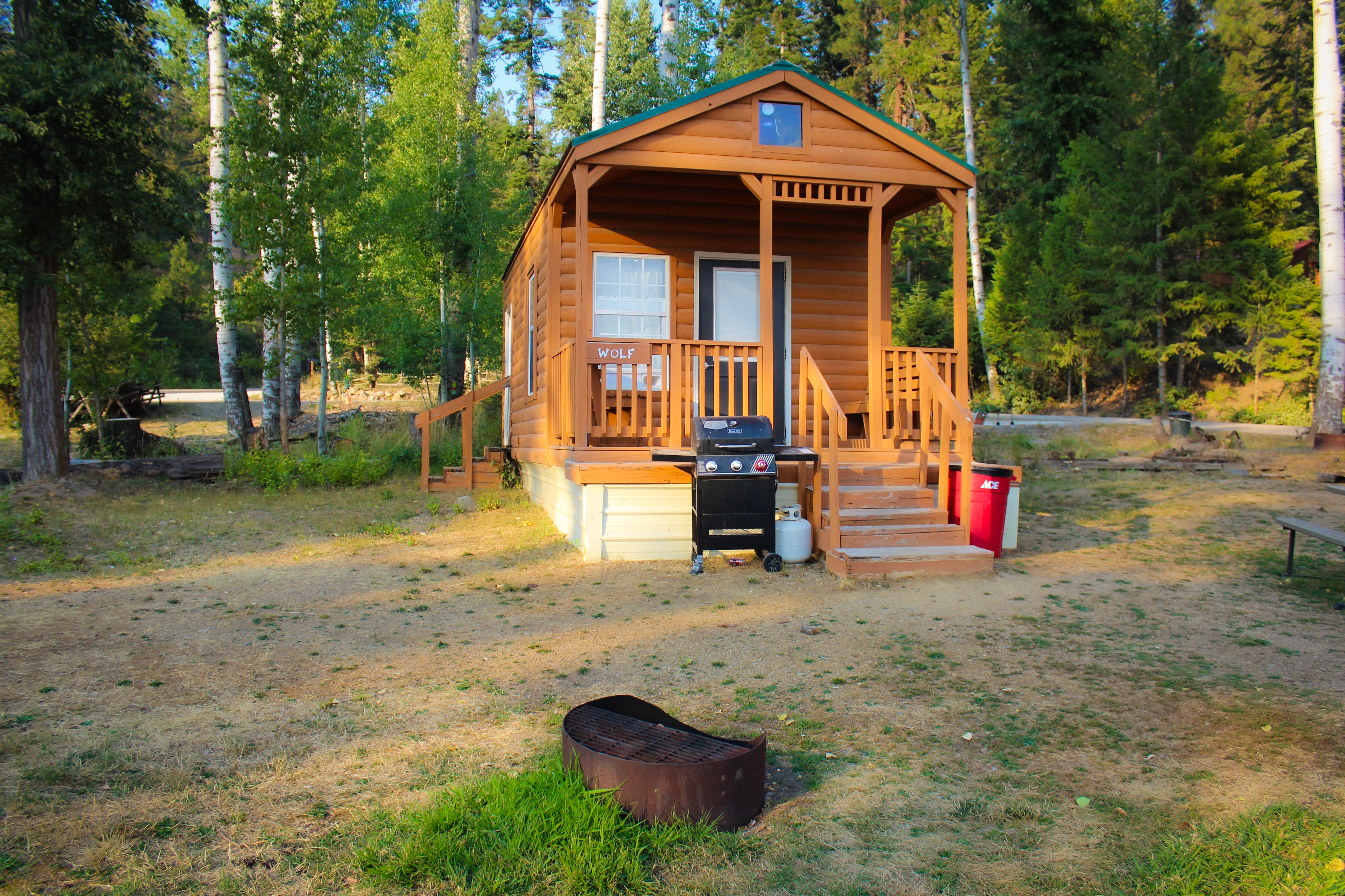 Loft Cabins - Wolf cabin with covered porch, BBQ grill, and fire pit in wooded setting