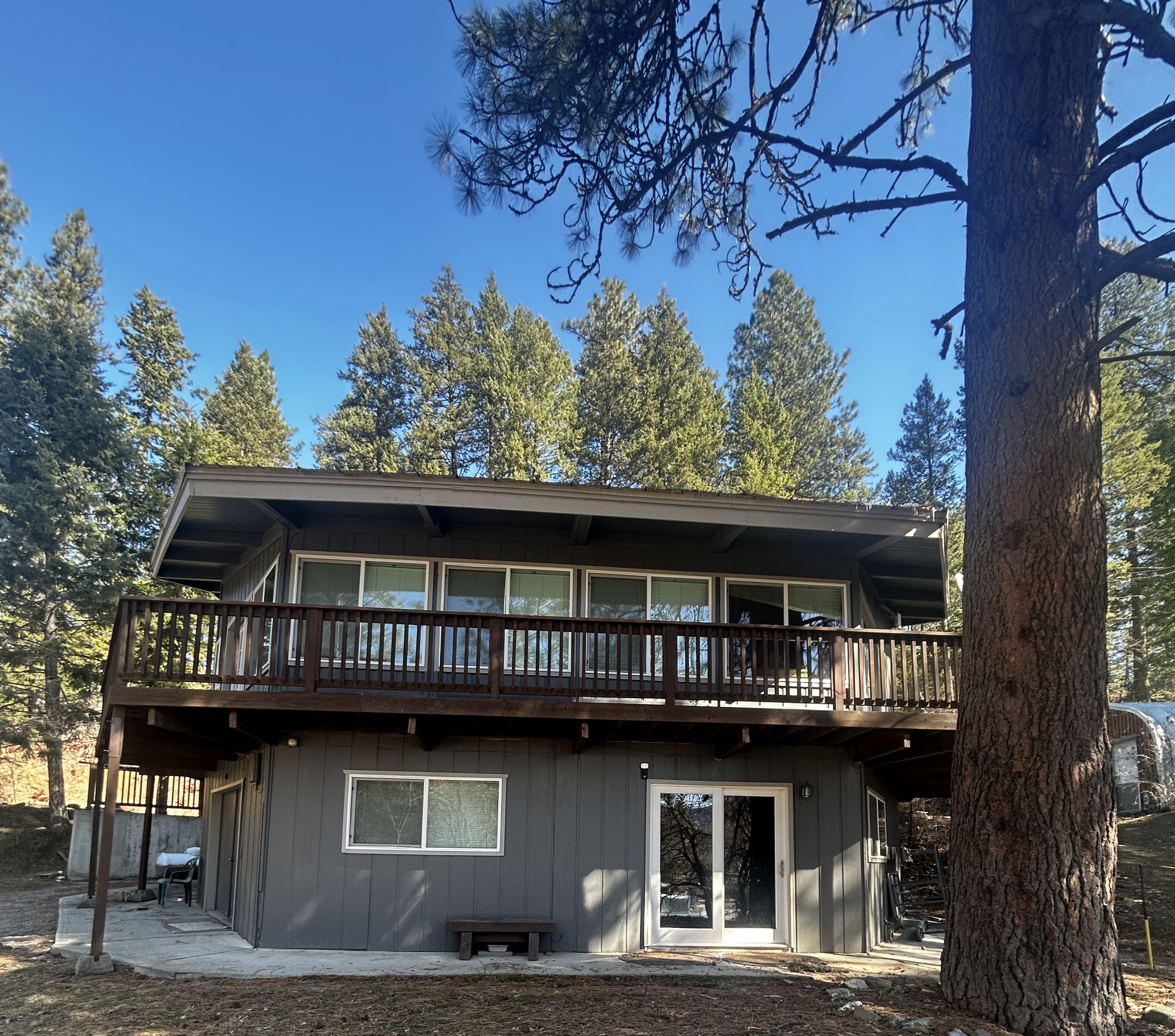 Resort House - Two-story house with wooden deck and balcony surrounded by pine trees